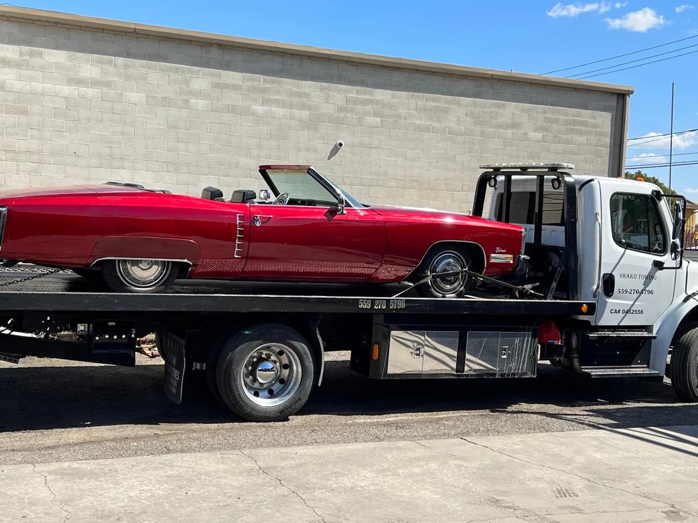 Shako Towing flatbed transporting a red classic convertible